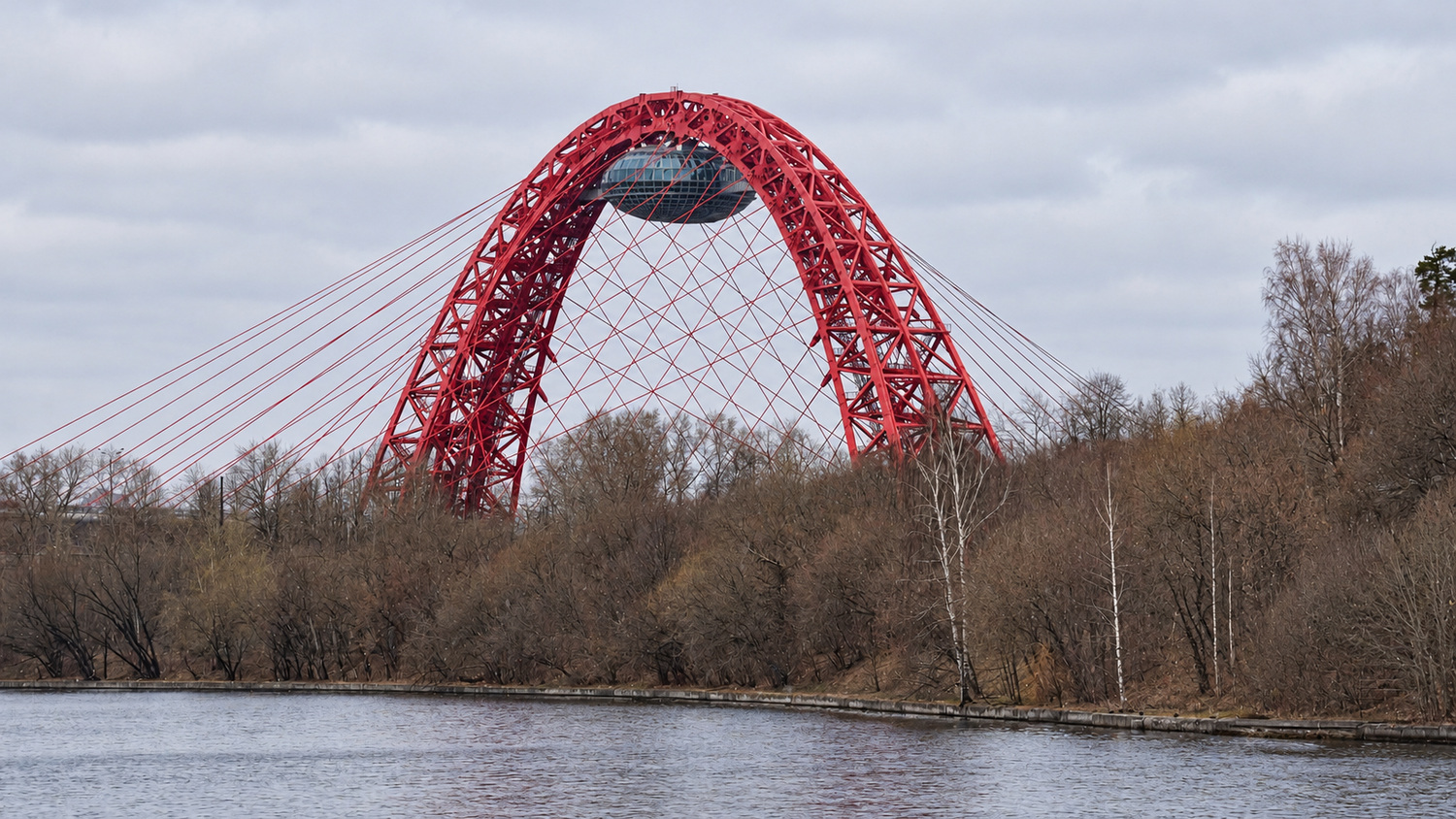 Красная арка Живописного моста над речным берегом